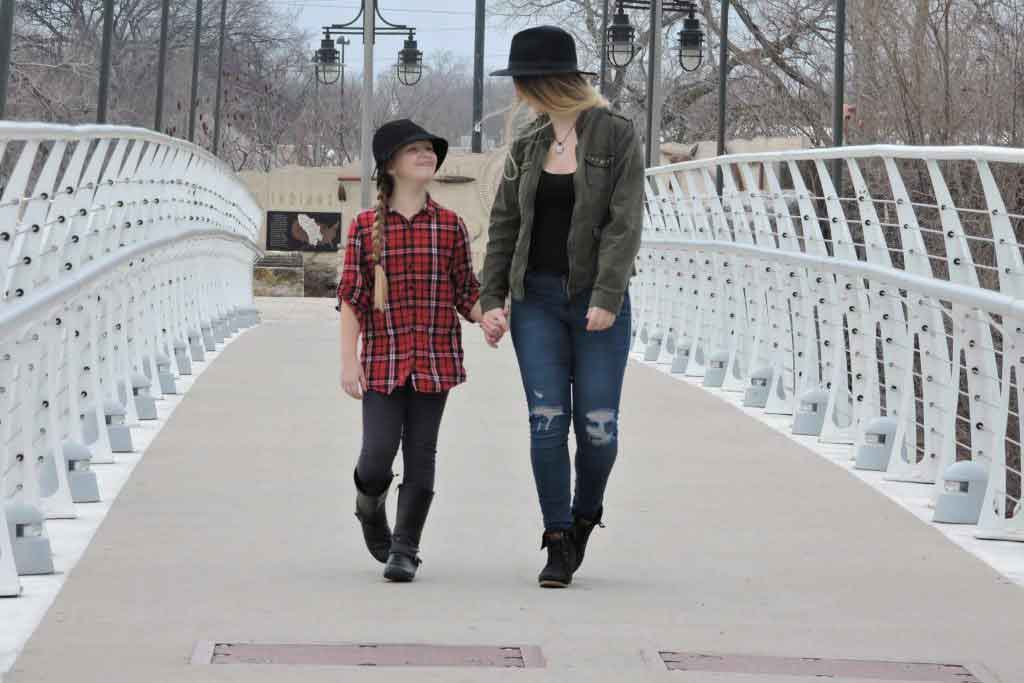 A woman and a girl walk across a bridge
